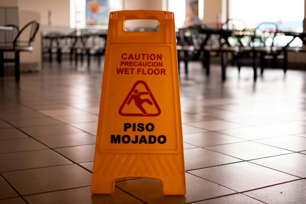 Yellow caution wet floor sign in a cafeteria warns of slippery conditions on tiled floor.